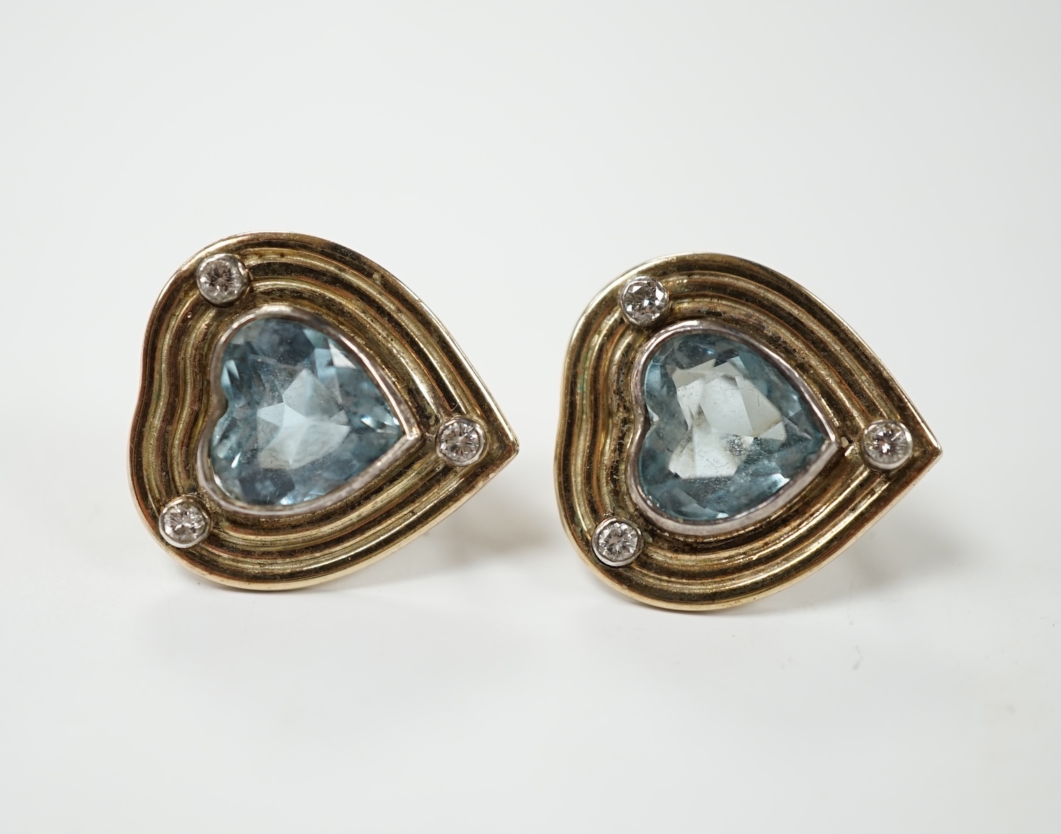 A pair of yellow metal, single stone heart shaped aquamarine and three stone diamond chip set earrings, 18mm, gross weight 7.5 grams. Condition - fair